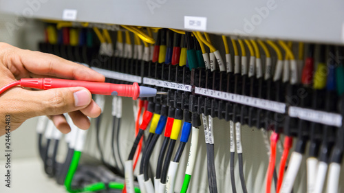 Electricians hands testing current electric in control panel.