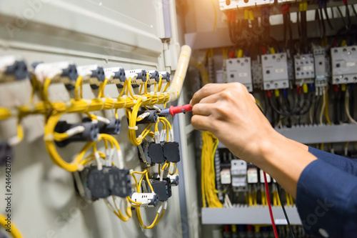 Electricians hands testing current electric in control panel.