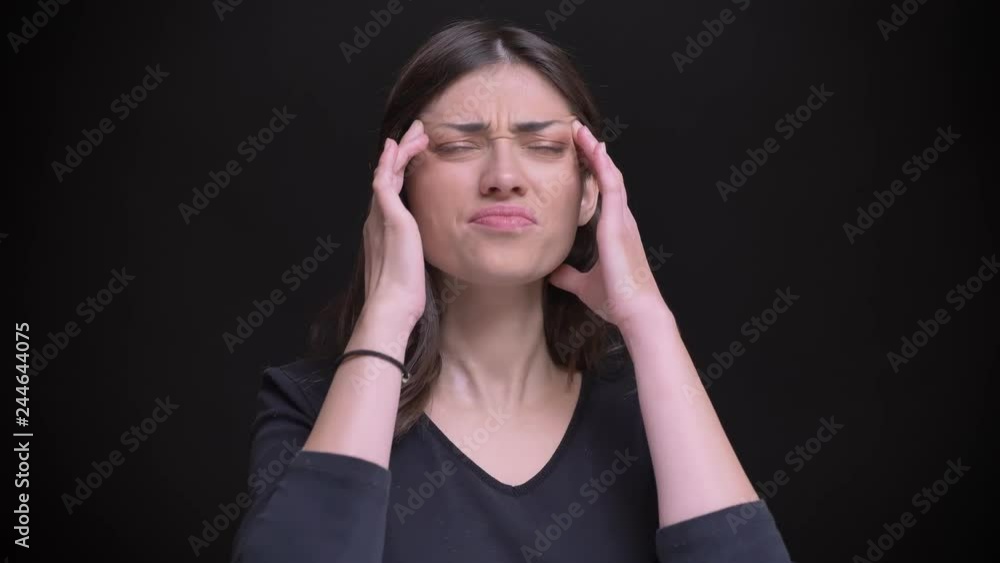Portrait of young caucasian long-haired brunette girl making massage and suffering from headache on black background. Portrait of young caucasian long-haired brunette girl making massage and suffering from headache on black background.