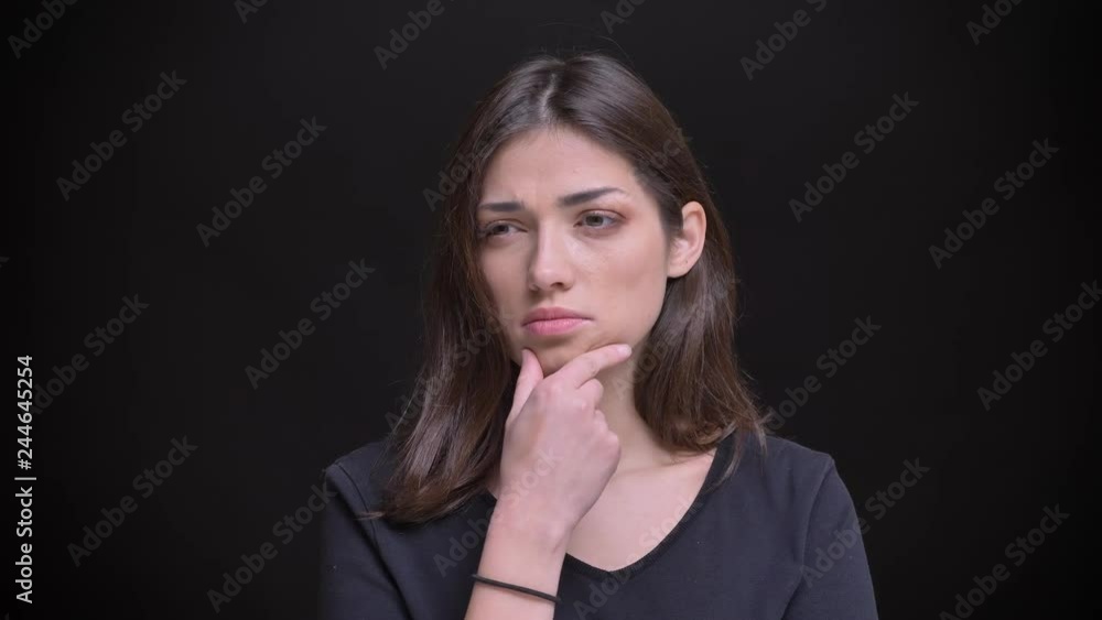 Portrait of young caucasian long-haired brunette girl watching thoughtfully on black background. Portrait of young caucasian long-haired brunette girl watching thoughtfully on black background.