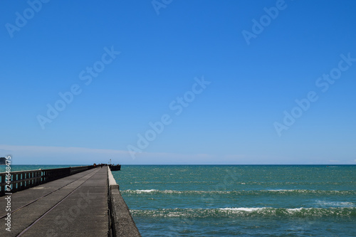 Scenic shot showing the length of the pier against the blue sea in Tolaga Bay, New Zealand.