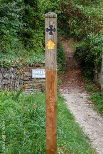 Signpost for the Saints´ Way with a black cross and an yellow arrow. The Saints´ way is a footpah which runs from Padstow to Fowey in Cornwall. photo