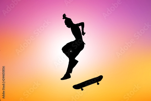 silhouette of skateboarder on blurry sunrise background.