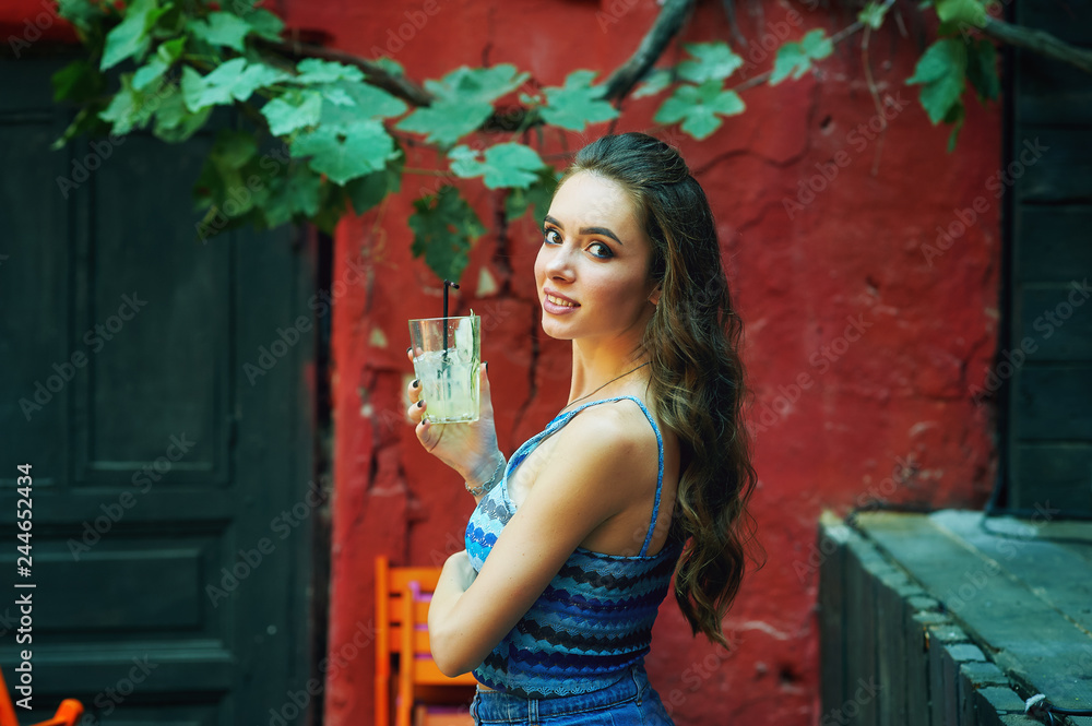Fototapeta premium Portrait of a young woman with a glass of soft drink in a cafe