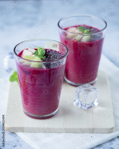 Glass of beetroot smoothie mix with apple, kiwi, chia seed and ice for detox and healthy drink on wood tray, black and white background.
