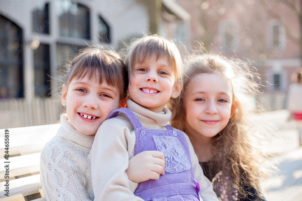 Obraz premium Three sisters sitting on bench in park.
