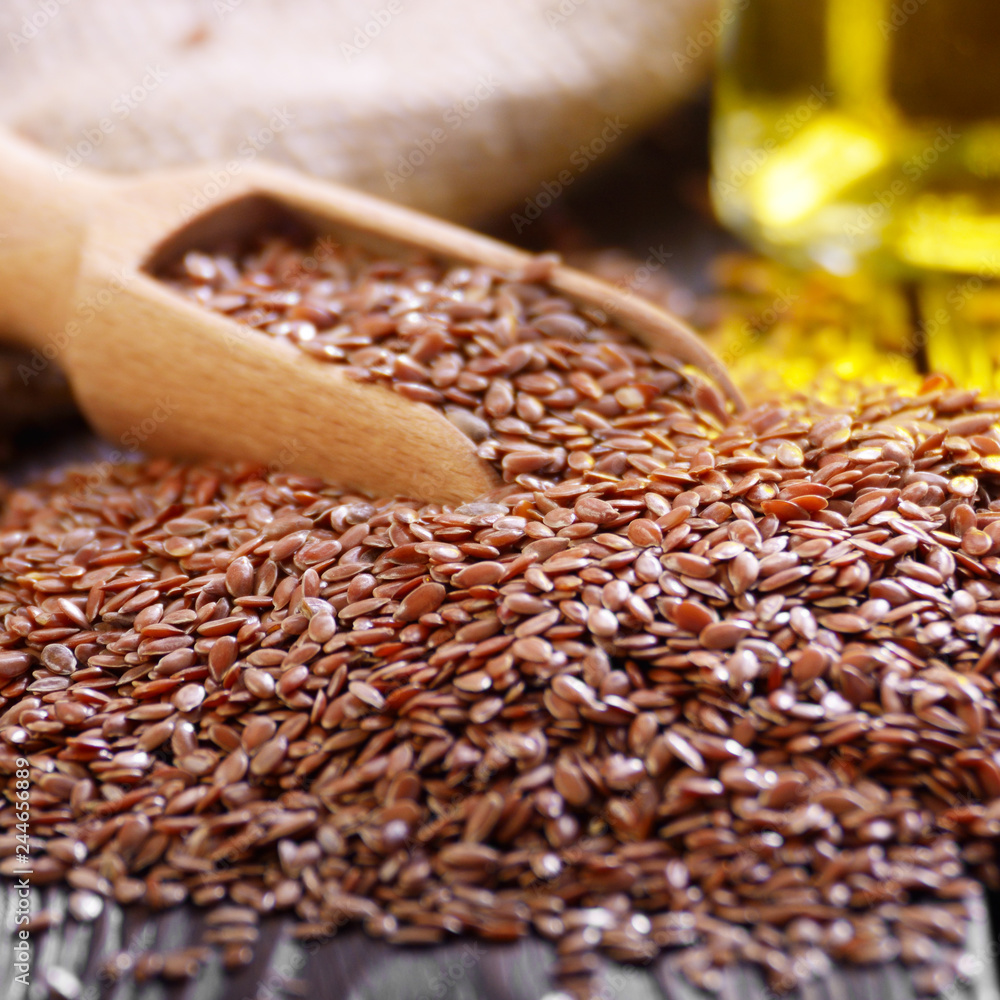 Flax oil and raw seeds in wooden scoop on kitchen table closeup Flax oil and raw seeds in wooden scoop on kitchen table closeup
