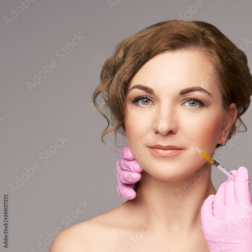 Face needle injection. Young woman cosmetology procedure. Doctor gloves. Lips