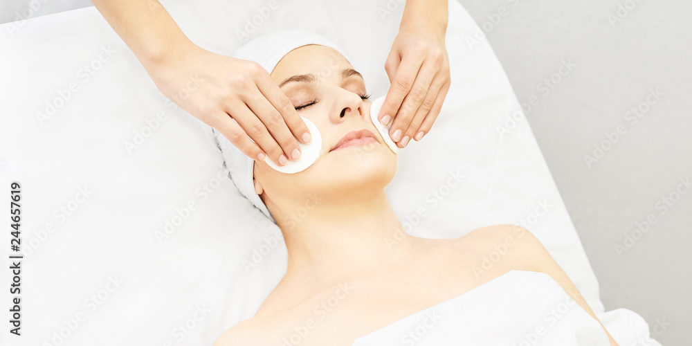 Cosmetology doctor remove mascara from girl face. Cotton pad with woman hands. Demakeup lotion