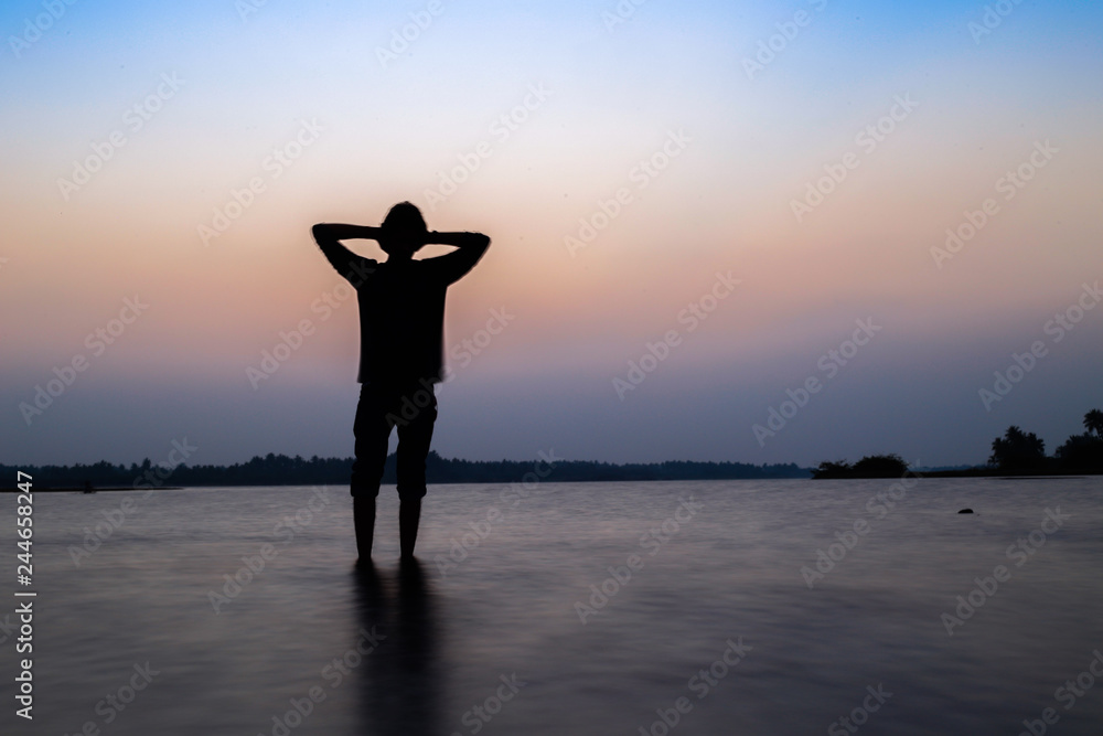 man standing in silhouette on sea