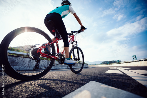 Woman cyclist legs riding Mountain Bike on highway