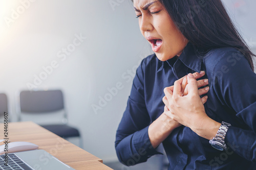 Working woman face suffering and holding breast because of heart infarction in office. photo