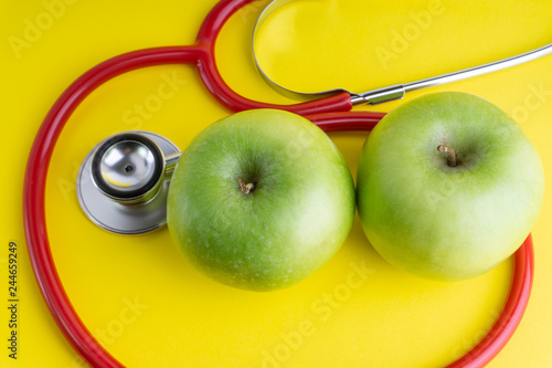 Green Apple with medical stethoscope isolated on yellow background for healthy eating. Selective focus and crop fragment. Healthy, Diet and copy space concept photo