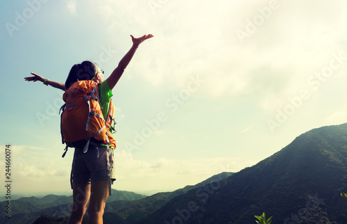 Cheering woman backpacker enjoy the view at mountain peak