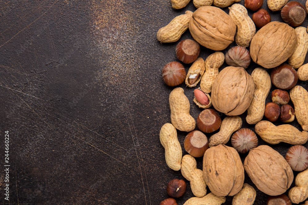 Copy space with nuts in a shell. Walnuts, hazelnuts and peanuts on dark background. Tasty healthy snack, food Copy space with nuts in a shell. Walnuts, hazelnuts and peanuts on dark background. Tasty healthy snack, food