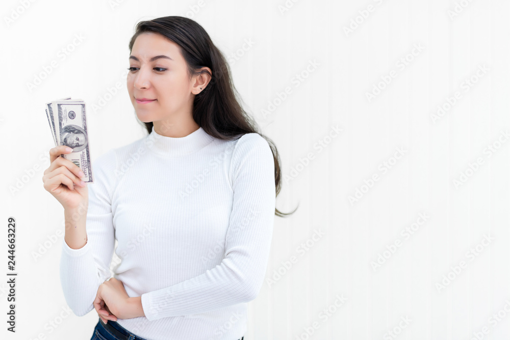 Attractive Asian woman hold bunch of dollars banknotes at office after success to invest in stock market with white wall background, money, cash, salary, investment and banking concept. Attractive Asian woman hold bunch of dollars banknotes at office after success to invest in stock market with white wall background, money, cash, salary, investment and banking concept.