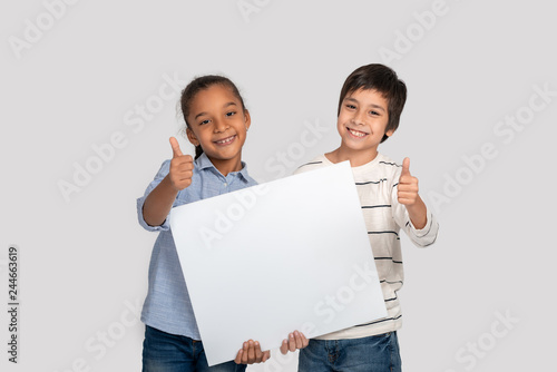 Studio shot of a boy and girl holding white plastic for writing ads or copy space photo