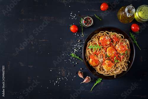 Italian pasta. Spaghetti with meatballs and parmesan cheese in black plate on dark rustic wood background. Dinner. Top view. Slow food concept