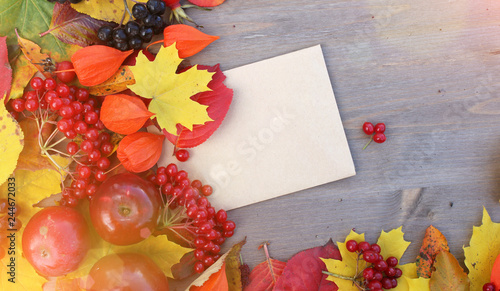 Thanksgiving background with apples, acorns, berries and fall leaves on the old wooden background. Autumn background with copy space. Abundant harvest concept.