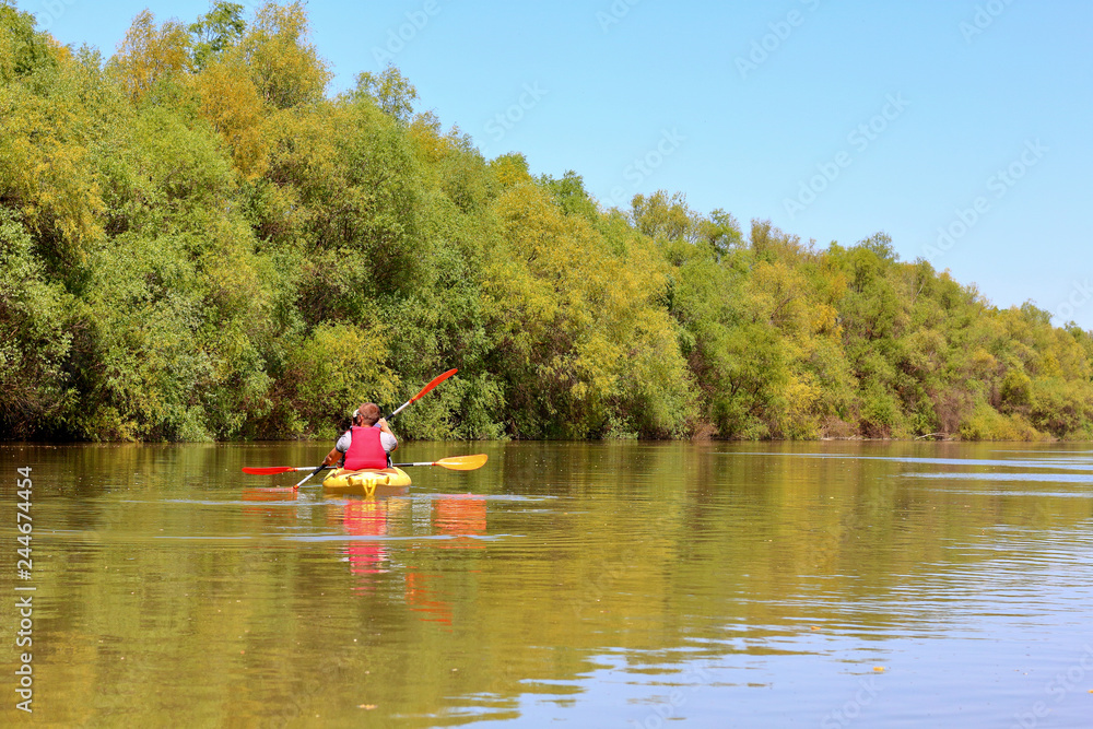 Couple (man and woman) paddle a yellow kayak at Danube river. Spring kayaking and water tourism and recreational