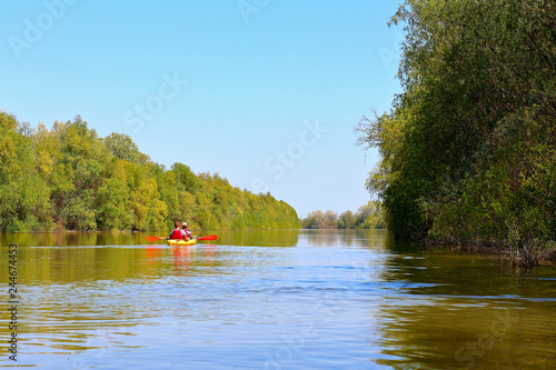 Couple (man and woman) paddle a yellow kayak at Danube river. Spring kayaking and water tourism and recreational © watcherfox