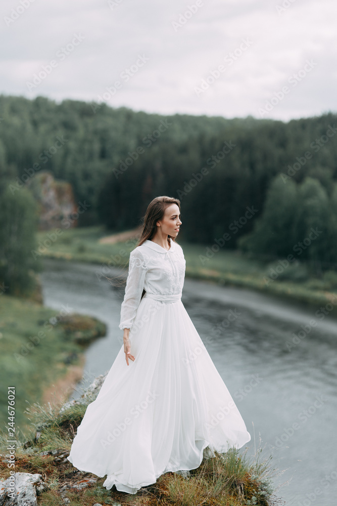 Morning bride on a beautiful panoramic location. Girl in boudoir dress and cliffs.