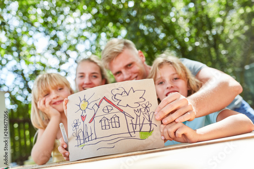 Familie zeigt bunte Zeichnung mit Eigenheim photo