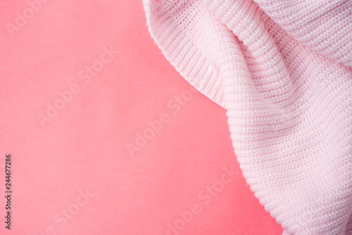 Pink knitted clothes on a pink paper background