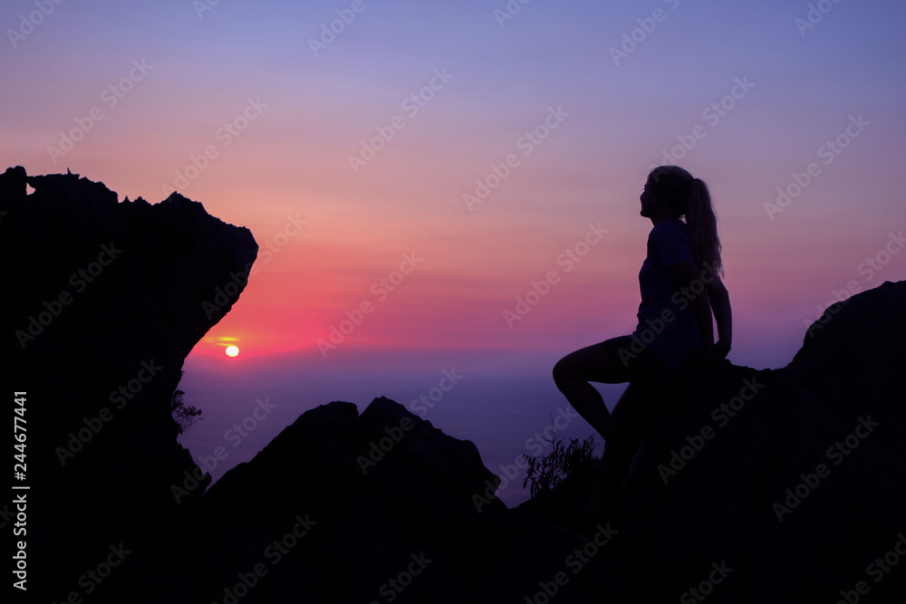 Happy woman enjoying on the top of the mountain at sunset.
