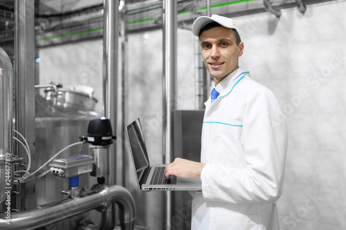 Technologist with a laptop in his hands at the dairy plant