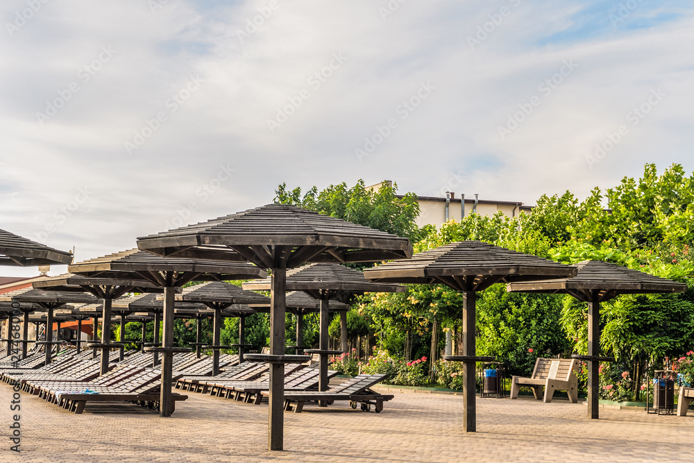 Brown wooden loungers and umbrellas. Empty rows resting places. Brown wooden loungers and umbrellas. Empty rows resting places.