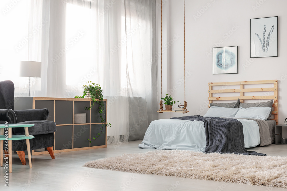 Fluffy white carpet on the floor of trendy bedroom with king size bed with wooden headboard