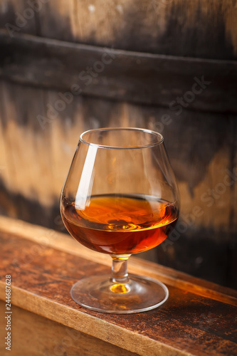 Glass of brandy near a barrel