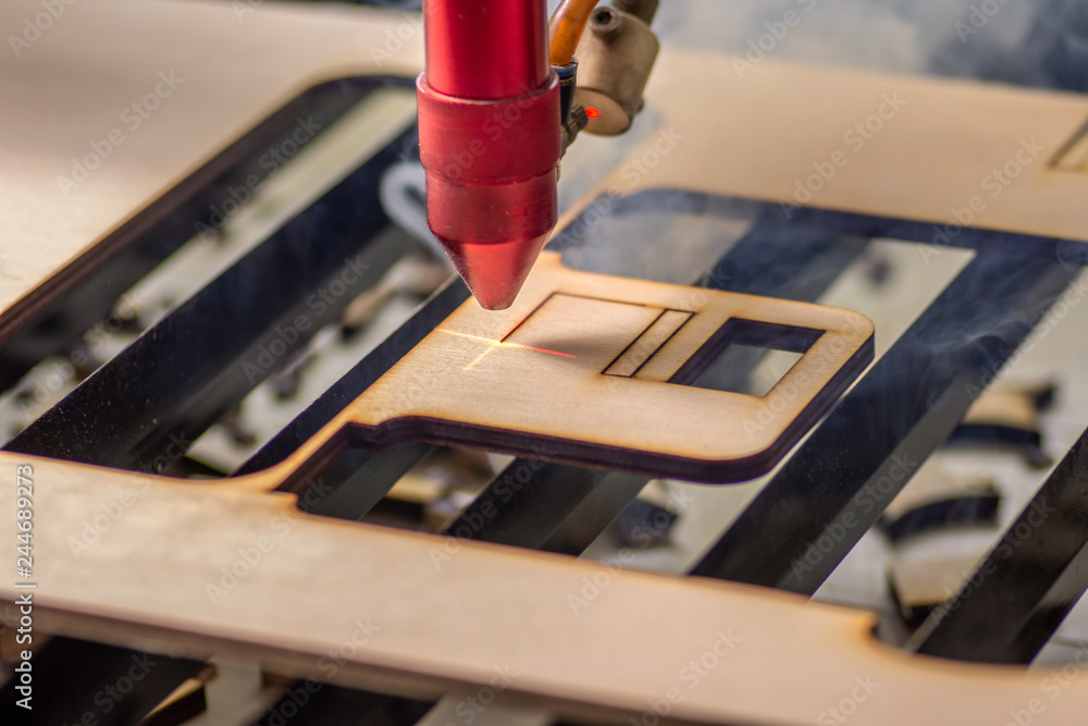 Obraz premium Laser engraver working and engraving wooden board