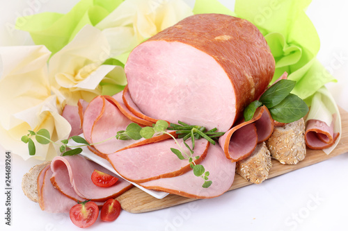 Szynka gotowana. Wędlina i warzywa na tle desek.