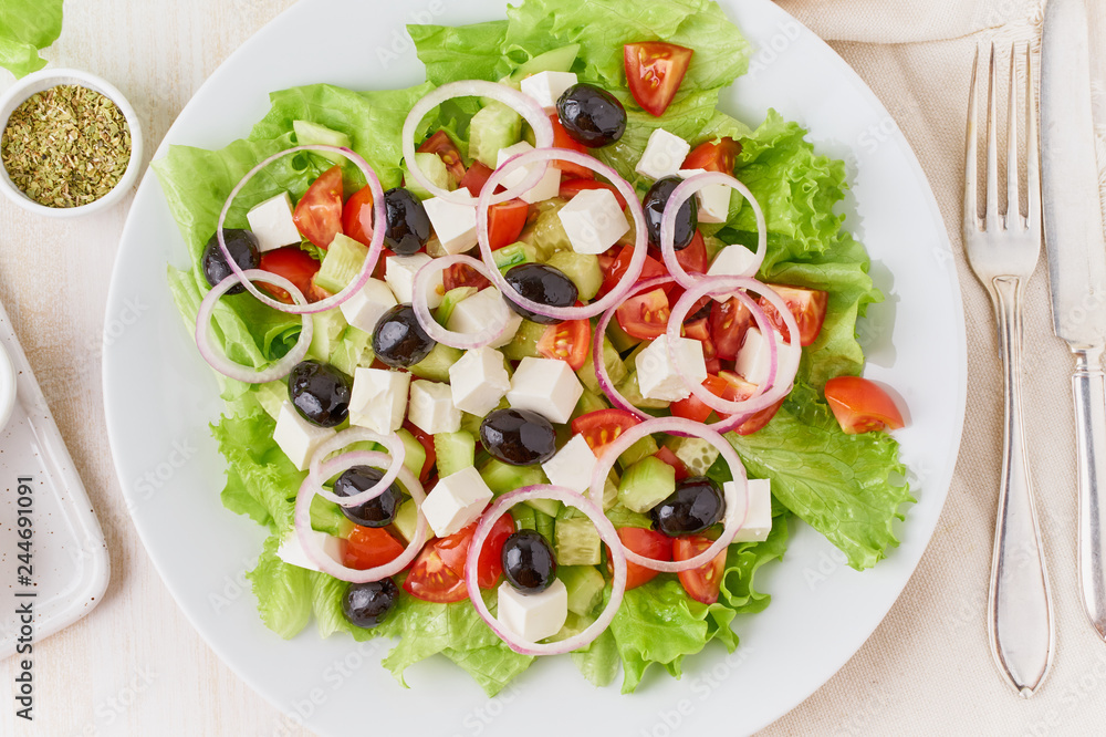 Greek salad on white plate on old rustic white wooden table, fresh salad with tomatoes, cucumbers, feta, onion. Top view Greek salad on white plate on old rustic white wooden table, fresh salad with tomatoes, cucumbers, feta, onion. Top view