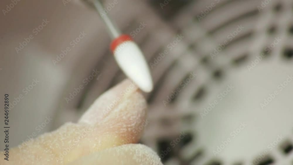 Professional hardware pedicure using electric machine. The manicurist grinded the nails of the girl in the nail salon and now gives them a form.