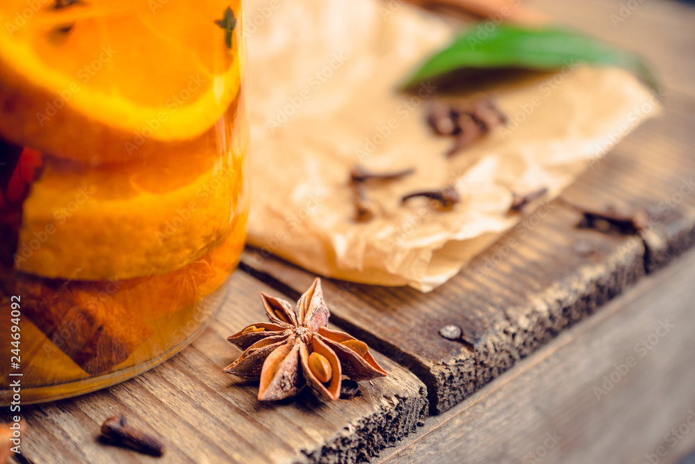 Spicy mandarines beverage in jar with cloves, anise and cinnamon. Selective focus. Shallow depth of field.