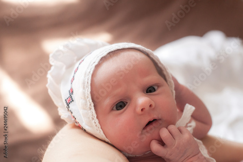 Tablou pe pânză Portrait of newborn baby in white hat, eyes squint