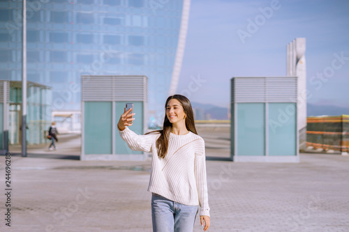 smiling girl taking a photo with 2 arms. City background - image