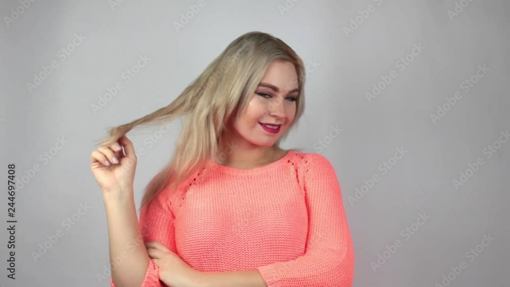 Pensive blonde woman in pink sweater looking around on white background Pensive blonde woman in pink sweater looking around on white background
