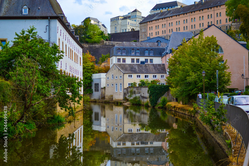 Alzette river crossing the old town of Luxembourg, Europe, with colorful typical houses and wall at the background