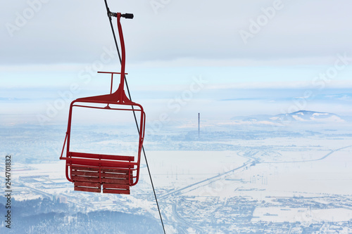 Empty old wooden chairlift against out of focus aerial urban area. Brasov, Romania.