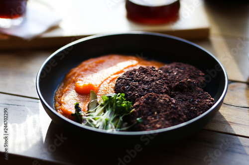 Vegan healthy black rice cutlets served with orange carrots mesh and microgreeens and decaf coffee. Vegeterian food.