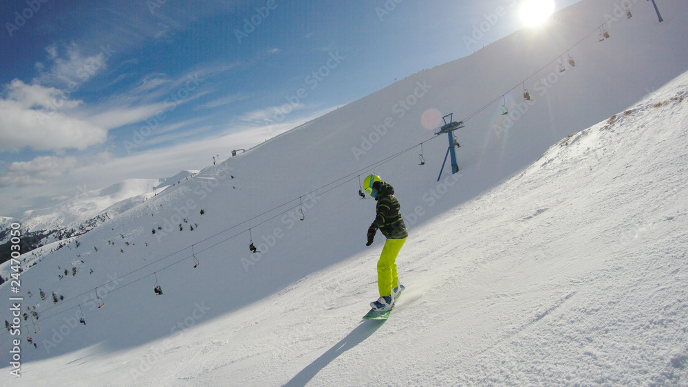 A girl rides a snowboard in the mountains. Lots of snow. Carpathians. Ski jacket and trousers.