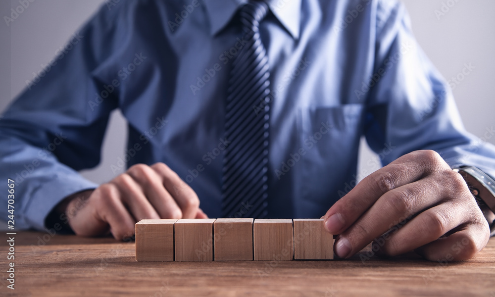 Businessman holding wooden cube on a wooden table. Businessman holding wooden cube on a wooden table.