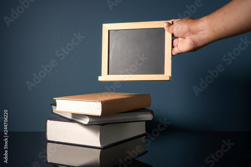 Hand holding blackboard and stalking books with low light