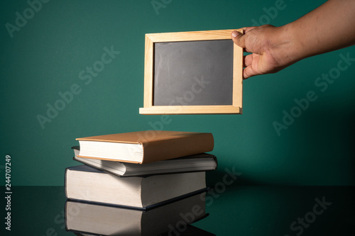 Hand holding blackboard and stalking books with low light