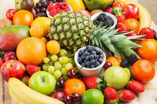 Healthy fruit background filled with strawberries raspberries oranges plums apples kiwis grapes blueberries mango persimmon pineapple  selective focus