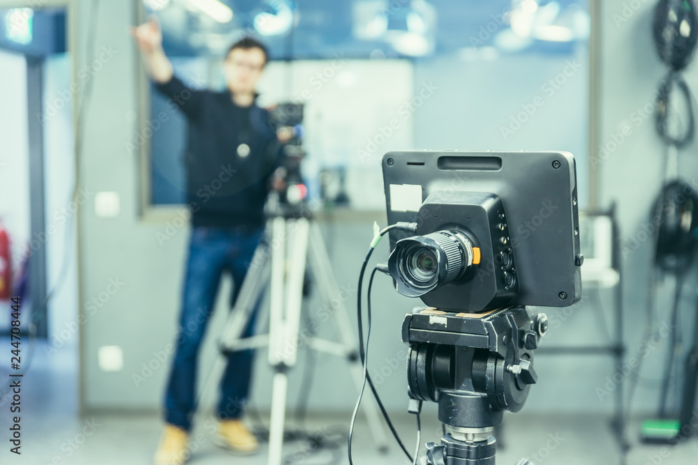 Film camera in broadcasting studio, spotlights and other equipment, cameraman in the blurry background Film camera in broadcasting studio, spotlights and other equipment, cameraman in the blurry background